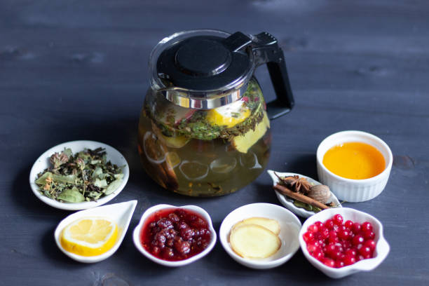 istock preparing healthy organic drink tea with apple, forest herbs, lemon, spices, ginger, raspberry jam, cranberries in glass teapot on black wooden background 1216842049