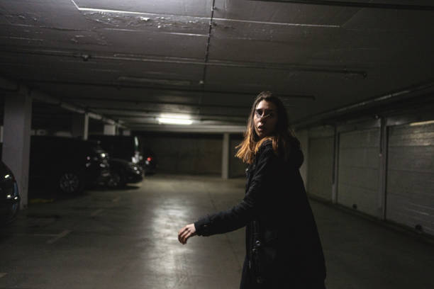 Scared woman running away from her abused in an underground parking lot Young woman looking over her shoulder while running away from a mentally abusing partner looking around stock pictures, royalty-free photos & images