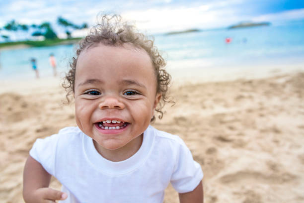 Cute smiling mixed race little boy playing at the beach