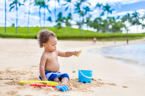 nette gemischte rasse kleiner junge spielen im sand auf einem tropischen strandurlaub - oahu water sand beach stock-fotos und bilder