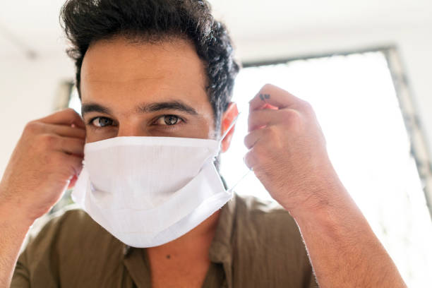 istock Man putting a face mask on his face 1216851964