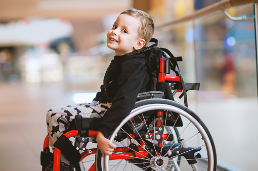 Cute little boy in wheelchair in shopping mall