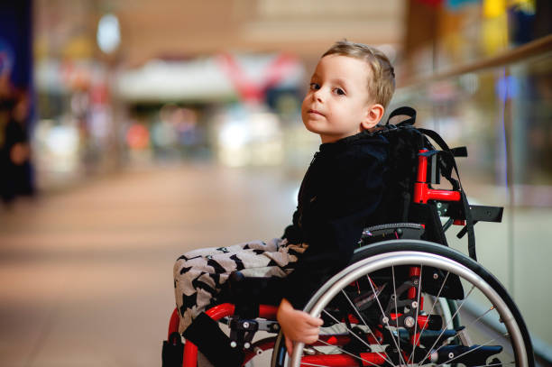 Cute little boy in wheelchair in mall stock photo