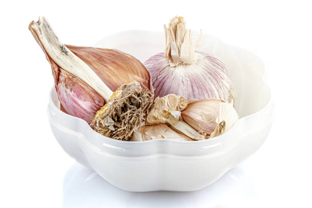 istock Garlic heads in open pearlescent plastic storage container in the shape of a garlic without cap isolated on white background with reflection on glossy surface 1216857788