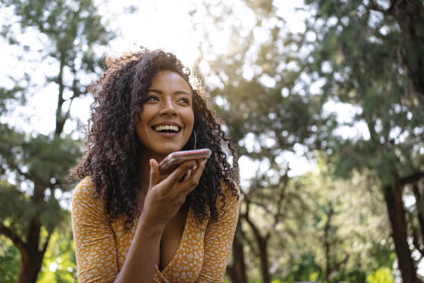 istock Joyful woman talking on her phone while relaxing in a park 1216858468