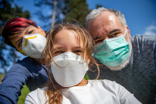 Little girl taking a Family selfie with Face masks outdoors