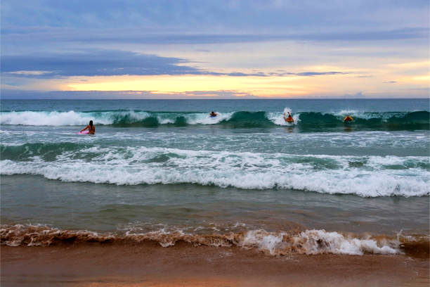 Scenic marine landscape with surfers enjoying Pacific ocean waves at Hapuna Beach State Park during sunset. Hawaii Big Island, USA.