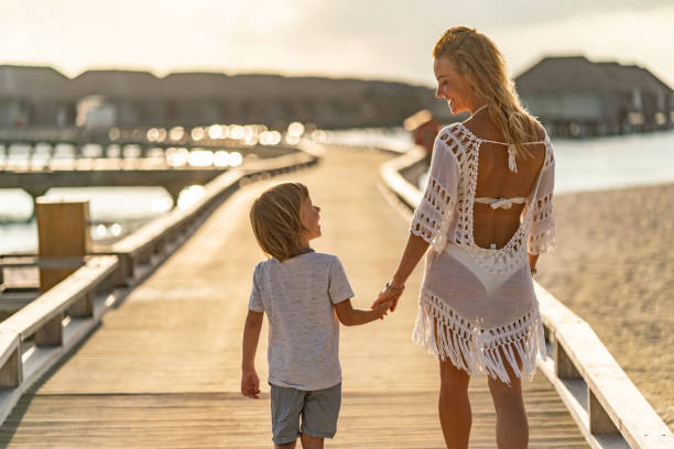 istock Mom and son walking on beach pier 1216865650