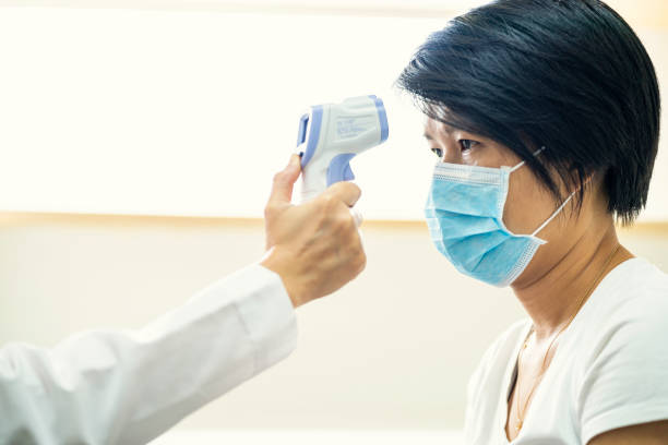 Female doctor using infrared forehead thermometer at hospital stock photo