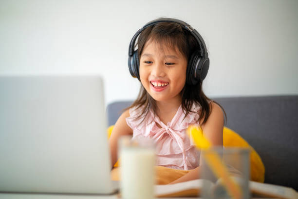 Asian girl using laptop for online study during homeschooling at home stock photo