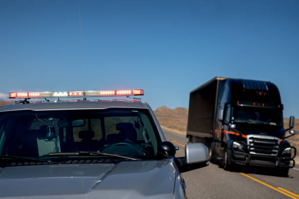 une voiture de patrouille d’autoroute de l’utah avec les lumières allumées, tirant un conducteur au-dessus, comme un camion semi conduit passé - semi truck truck red truck driver photos et images de collection