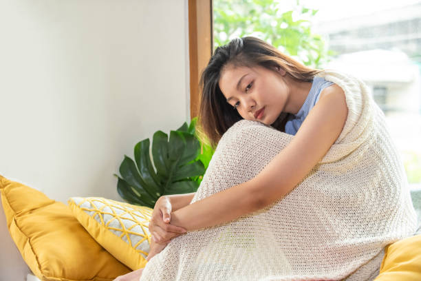 soledad hermosa mujer asiática chica con manta sentada sola en la habitación. adolescente deprimida pensando en el problema con la tristeza cara y la emoción negativa. concepto de salud mental y tema social. - abrazar las rodillas fotografías e imágenes de stock