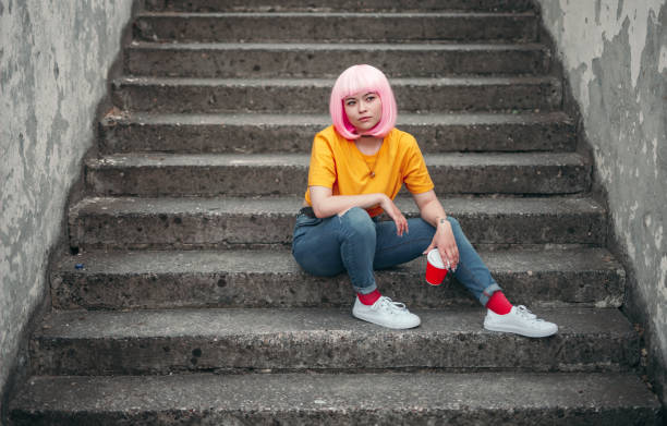модный азиатский подросток, сидящий на ступеньках - child looking messy urban scene стоковые фото и изображения