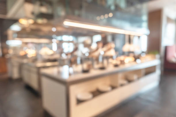 istock Buffet at hotel restaurant interior blur background with blurry open kitchen counter bar of food catering service business with chef staff cooking for breakfast, lunch or dinner meal 1216869756