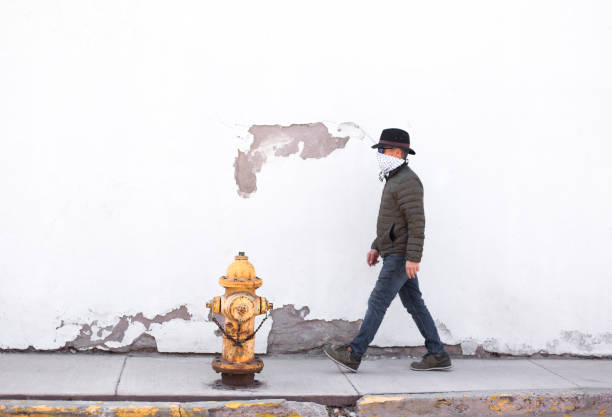 istock Man Walking Down Sidewalk Wearing Bandana Mask 1216871621