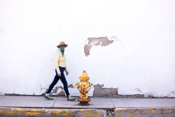 istock Woman Walking Down Sidewalk Wearing Bandana Mask 1216872192