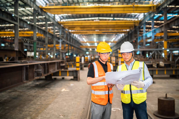 istock Asian engineers looking at blueprint documents in a factory 1216889235