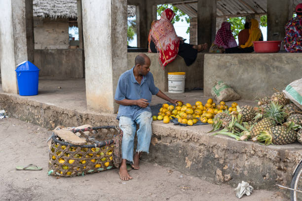 l'uomo africano vende frutta tropicale in un mercato locale di cibo di strada sull'isola di zanzibar, tanzania, africa orientale - africa agriculture zanzibar industry foto e immagini stock