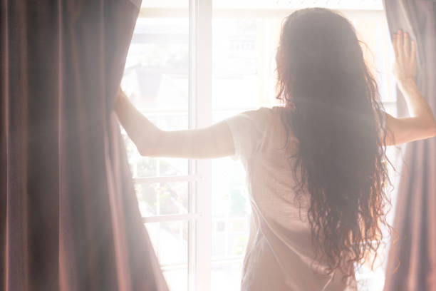 istock Woman opens the curtains in the morning 1216905946