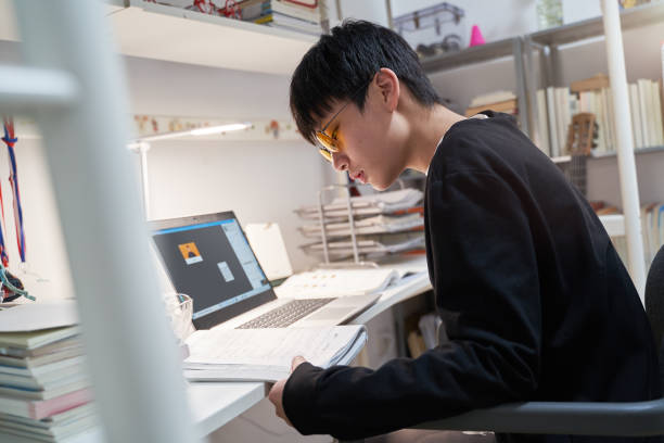 Asian kid learning from home on laptop in his bedroom stock photo