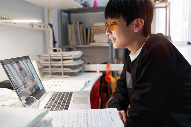 Asian kid learning from home on laptop in his bedroom stock photo