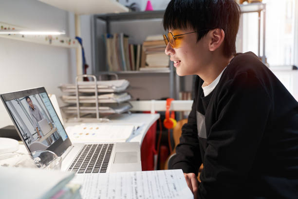 Asian kid learning from home on laptop in his bedroom Chinese teenager studying from home during covid-19 quarantine wearing computer glasses male chinese student stock pictures, royalty-free photos & images