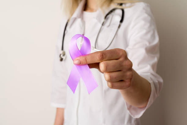 Woman doctor holding a purple ribbon in her hands Woman doctor holding a purple ribbon in her hands - image cancer screening stock pictures, royalty-free photos & images