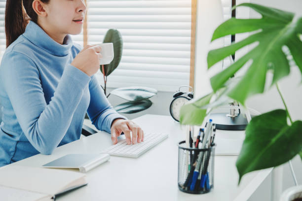 istock Asian woman working from home using computer and drinking coffee in her bedroom document finance and conference online meeting for new projects 1216908231