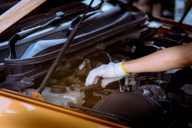 a woman car mechanic repairing car with open hood view and checking level motor oil for refill or clean in car garage service - vehicle breakdown hood car oil change imagens e fotografias de stock