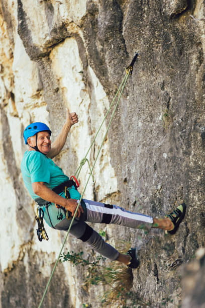 istock Senior man with a rope climbing on the rock. 1216912393
