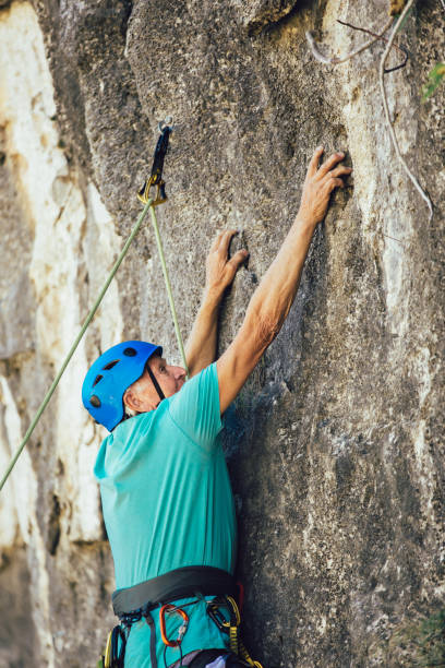 istock Senior man with a rope climbing on the rock. 1216912472