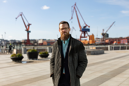 A man with a beard and glasses is standing by the Gothenburg harbour.