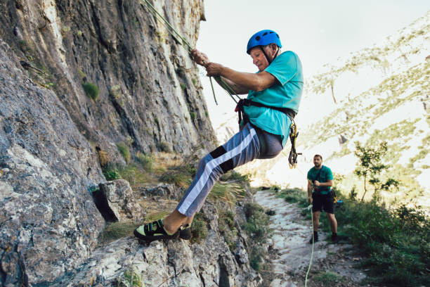 istock Senior man with a rope climbing on the rock. 1216912837