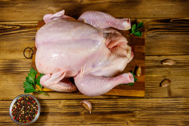 istock Raw whole chicken with spices on a wooden table. Top view 1216913797