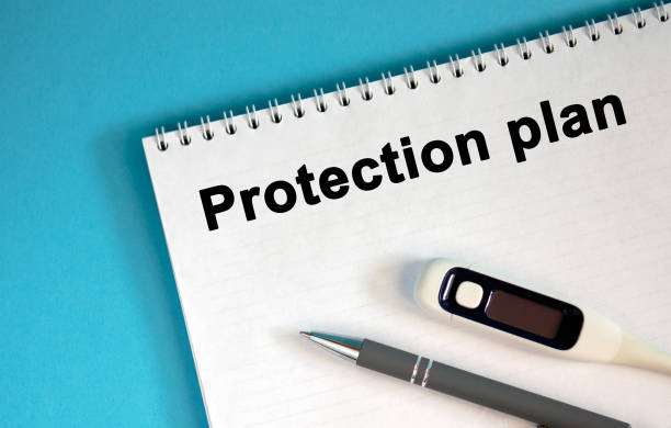 istock PROTECTION PLAN - text on a notepad. Lie a pen and a medical thermometer 1216915345