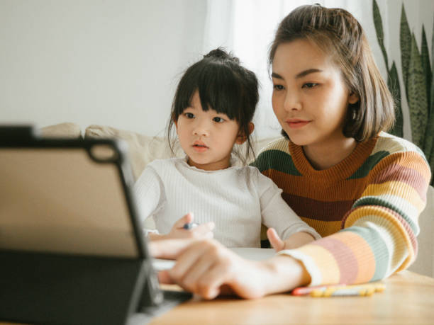 madre ayudando a la niña con el trabajo o la tarea - child digital tablet mother teaching fotografías e imágenes de stock