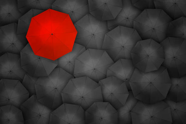 istock Red umbrella over many dark ones 1216918403