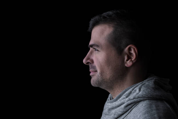 istock Side studio portrait of a serious man looking sideways. Isolated on black background. 1216922612