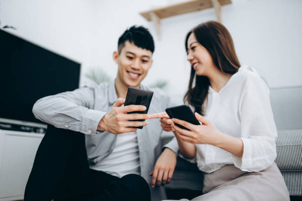 istock Young Asian couple using smartphone for entertainment during self isolation at home in Covid-19 health crisis 1216924471