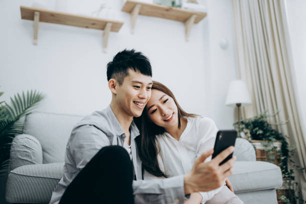 istock Young Asian couple using smartphone for entertainment during self isolation in Covid-19 health crisis 1216924563