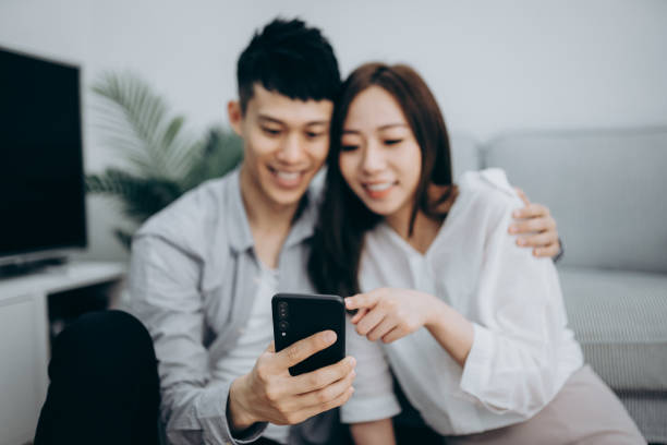 istock Young Asian couple using smartphone for entertainment during self isolation in Covid-19 health crisis 1216924681