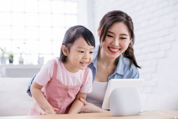 Smart AI speaker concept Smart AI speaker concept - Mom and daughter talk to voice assistant with screen at home happily smart home family stock pictures, royalty-free photos & images
