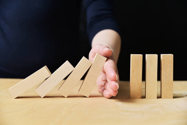 istock Manager stopping collapsing dominos with her hand 1216925465