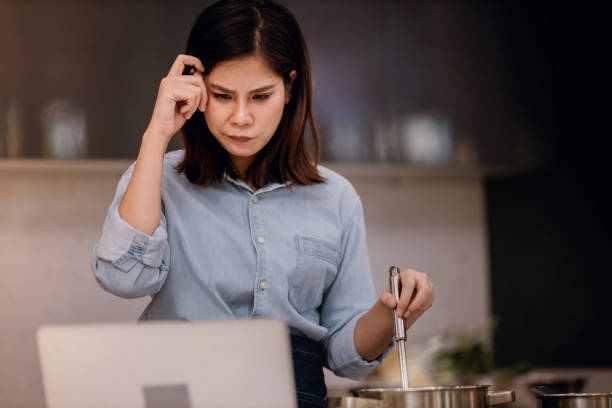 E-Learning Concept. Young Woman Try to Practice and Learn for Cooking at Home via the Internet