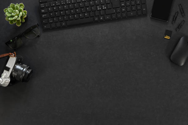 istock Top view of black concrete office desk with computer, camera and supplies 1216926532