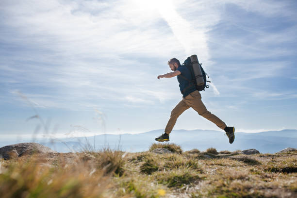 istock Mature man with backpack hiking in mountains in summer, jumping. 1216926977