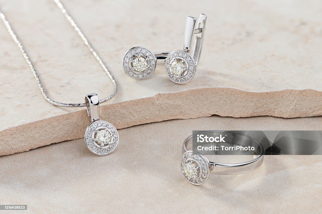 Elegant jewelry set of white gold ring, necklace and earrings with diamonds Elegant jewelry set of white gold ring, necklace and earrings with diamonds. Silver jewellery set with gemstones. Product still life concept Jewelry Stock Photo