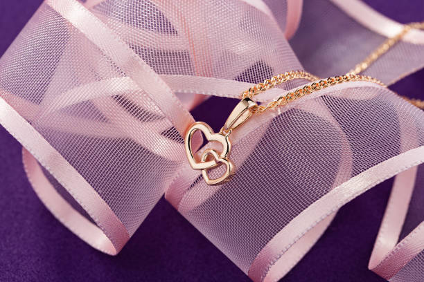Hearts shape rose gold pendant necklace on pink background stock photo