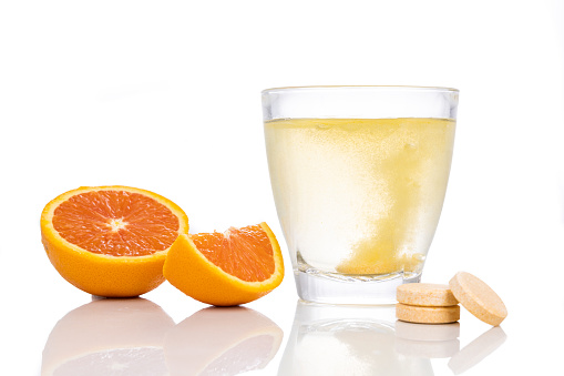 Serie de comprimidos efervescentes con sabor a naranja de vitamina c caídos y disueltos en vaso de agua photo