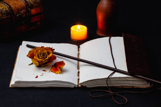 istock Image of open magic book, wand, burning candle 1216929555